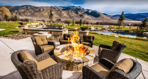 A cozy outdoor seating area with a fire pit, surrounded by mountains and a serene landscape.